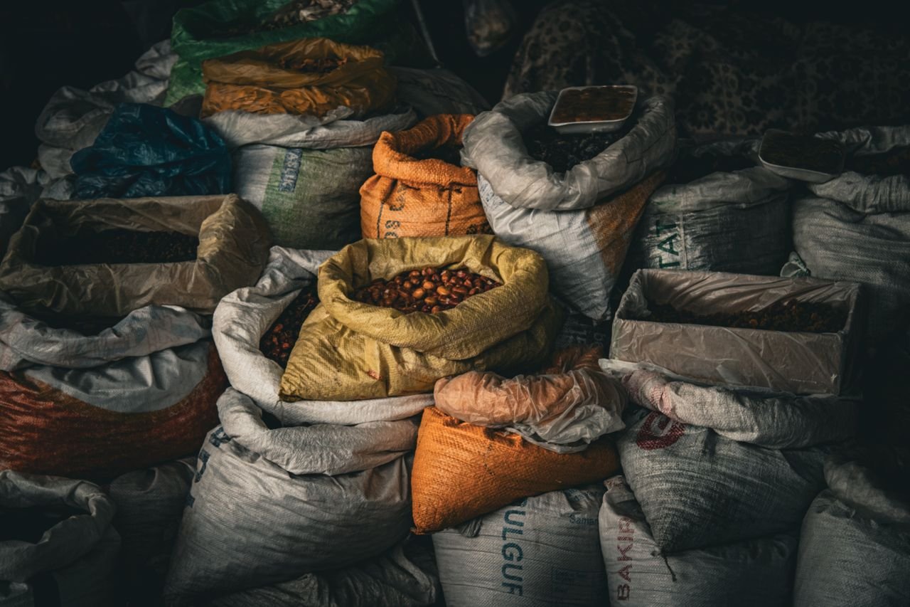 Services A variety of grains and spices in vividly colored sacks at an indoor market, providing rich textures.